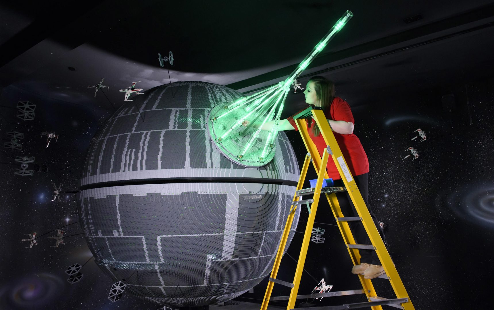 ONE OF THE WORLD’S BIGGEST EVER LEGO® STAR WARS™ MODELS INSTALLED AT THE LEGOLAND® WINDSOR RESORT. LAST PIECES PUT IN PLACE ON 500,000 LEGO® BRICK DEATH STAR. LEGOLAND® Model Maker, Phoebe Rumbol, puts the finishing touches to one of the most impressive and biggest LEGO® Star Wars™ models ever created as a 500,000 brick LEGO® Star Wars™ recreation of The Death Star is installed in a new finale to the Resort’s LEGO® Star Wars™ Miniland Model Display. The operation took three days as the massive new 2.4 metre wide, 3 metre high creation was carefully hoisted into position and the final bricks  were put in place. The hefty 860kg perfectly spherical model took 15 Model Makers three months to build and  guests can trigger special effects and bring the scene to life when it opens at the Resort on 11 March.  TM & © Lucasfilm Ltd. All rights reserved