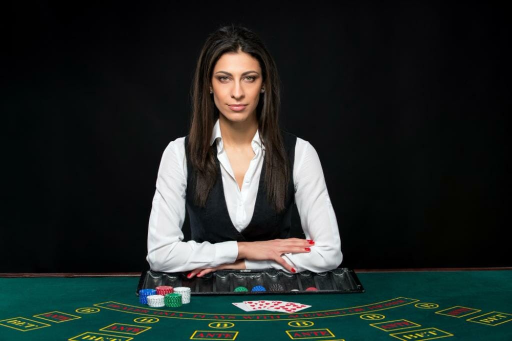 beautiful girl dealer table game poker dealer deals cards he is looking camera