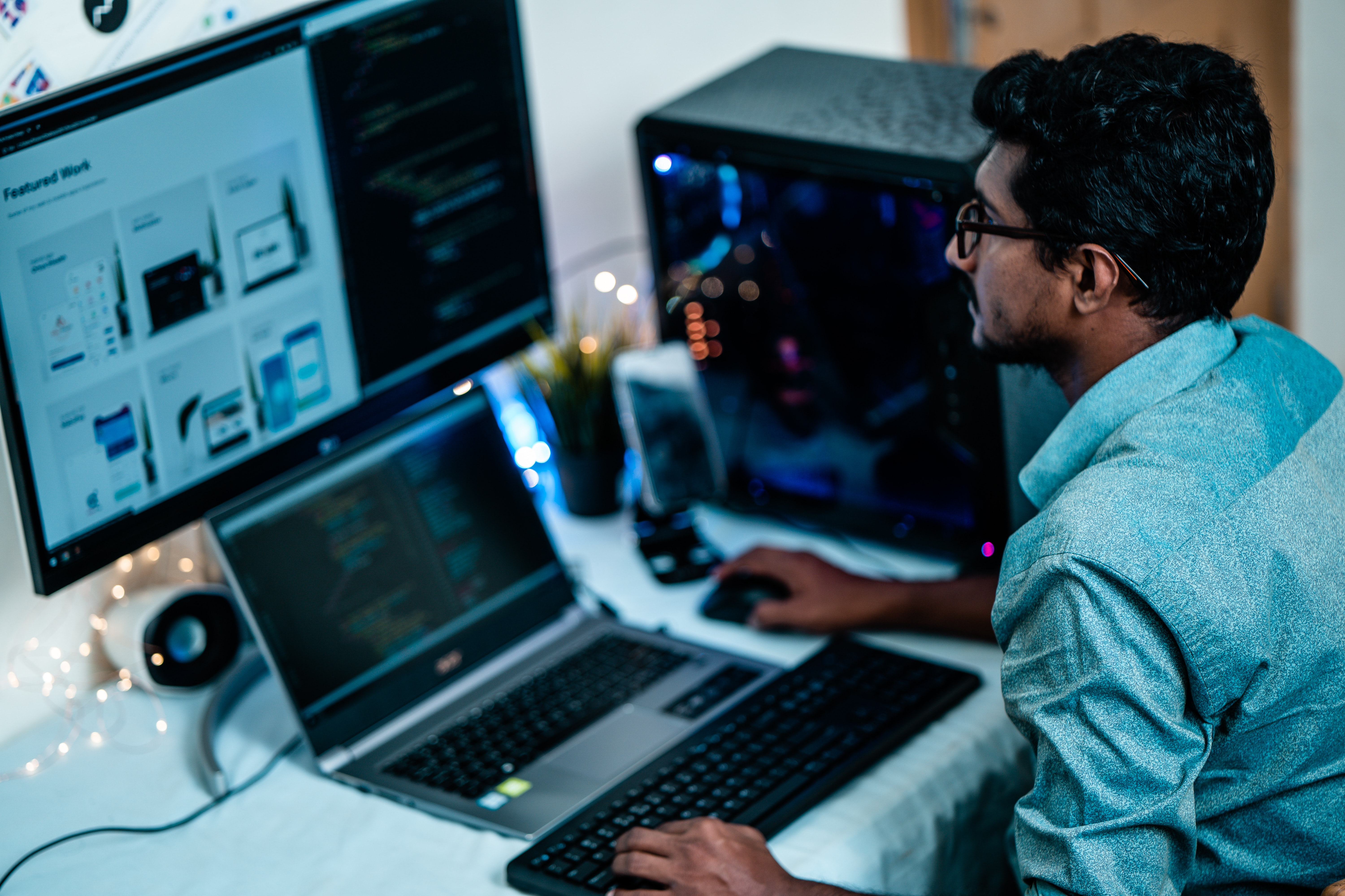 Man working at his laptop with a large monitor in front of him.